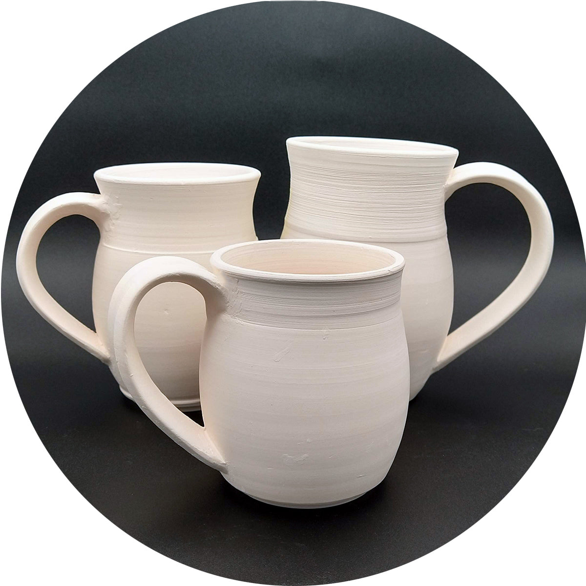 Three unfired mugs on a black background